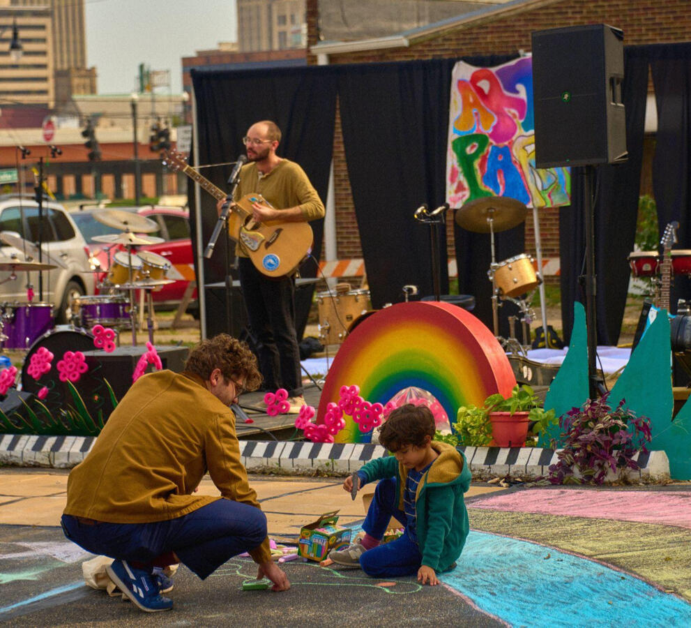 An adult and a child patron enjoying a colorful outdoor music festival called Art Parkd